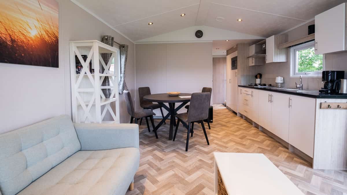 Woonkamer met grijze bank, open keuken en ronde eettafel