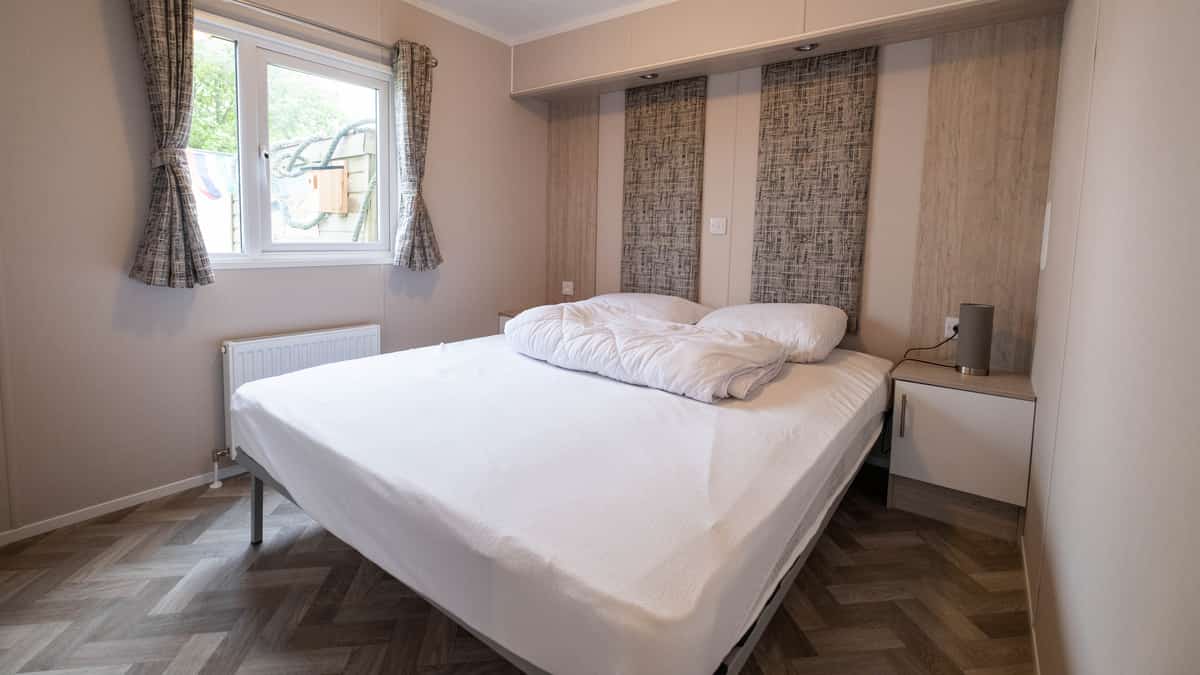 Slaapkamer met wit bed, raam en gordijnen met patroon