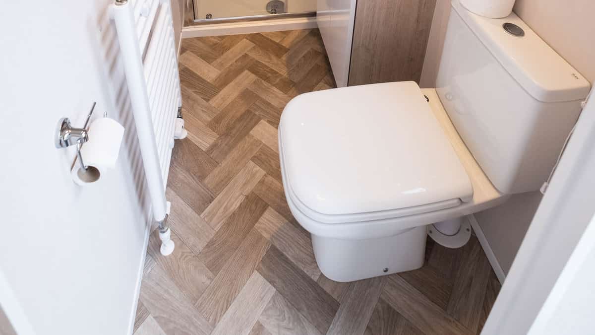 Badkamer met glazen douchecabine, wastafel, toilet en handdoekradiator