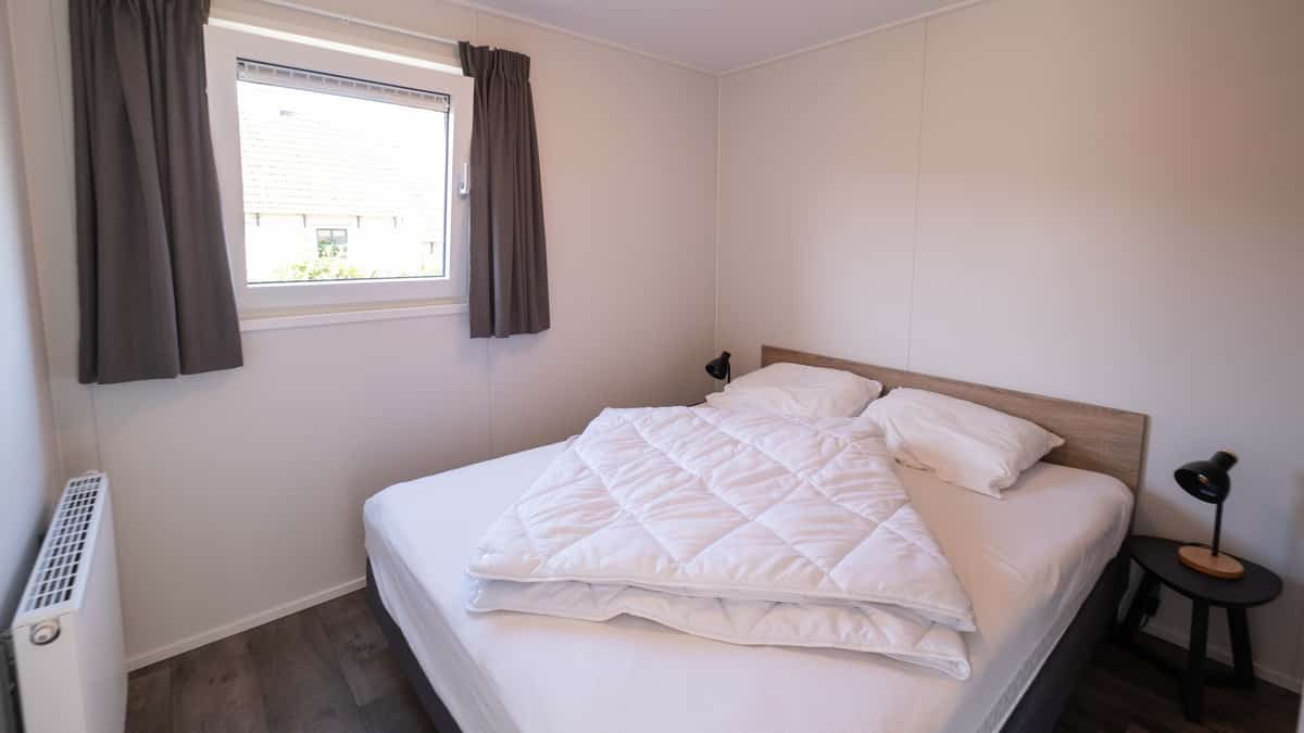 Slaapkamer met tweepersoonsbed in Chalet Deluxe Marcel op Camping Cupido