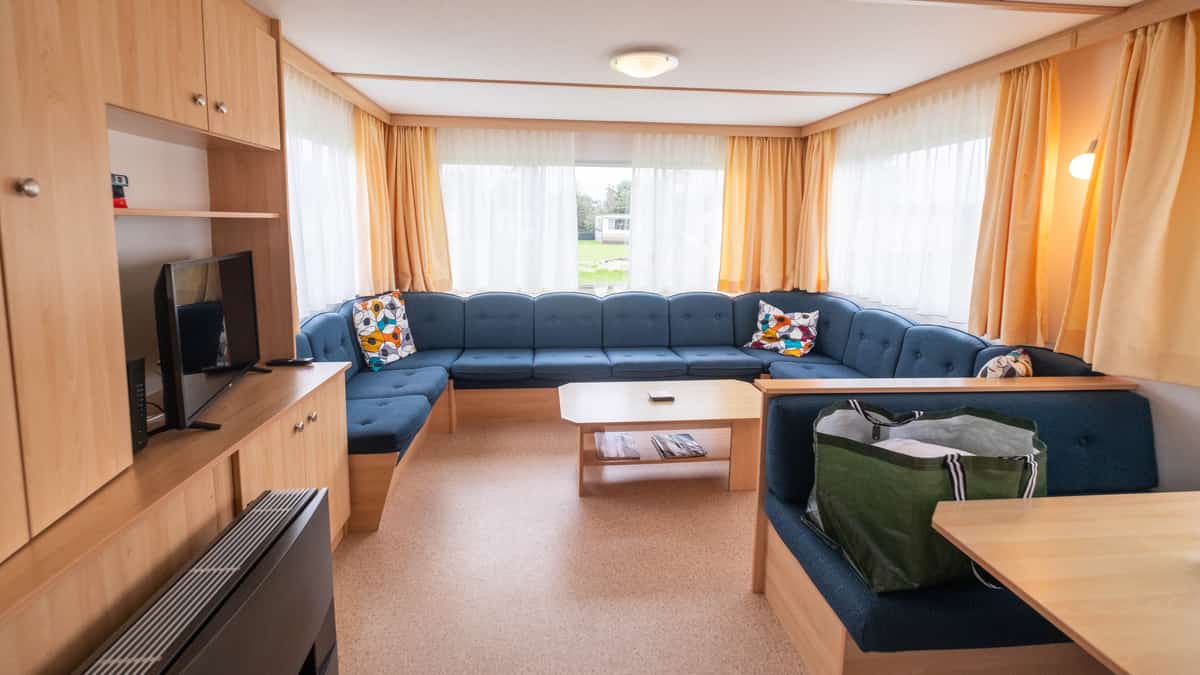 Woonkamer met hoekbank in stacaravan Wulk op Camping Cupido