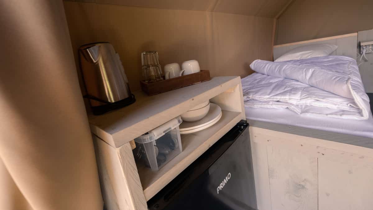 Twee bedden met wit beddengoed naast een wastafel en waterkoker