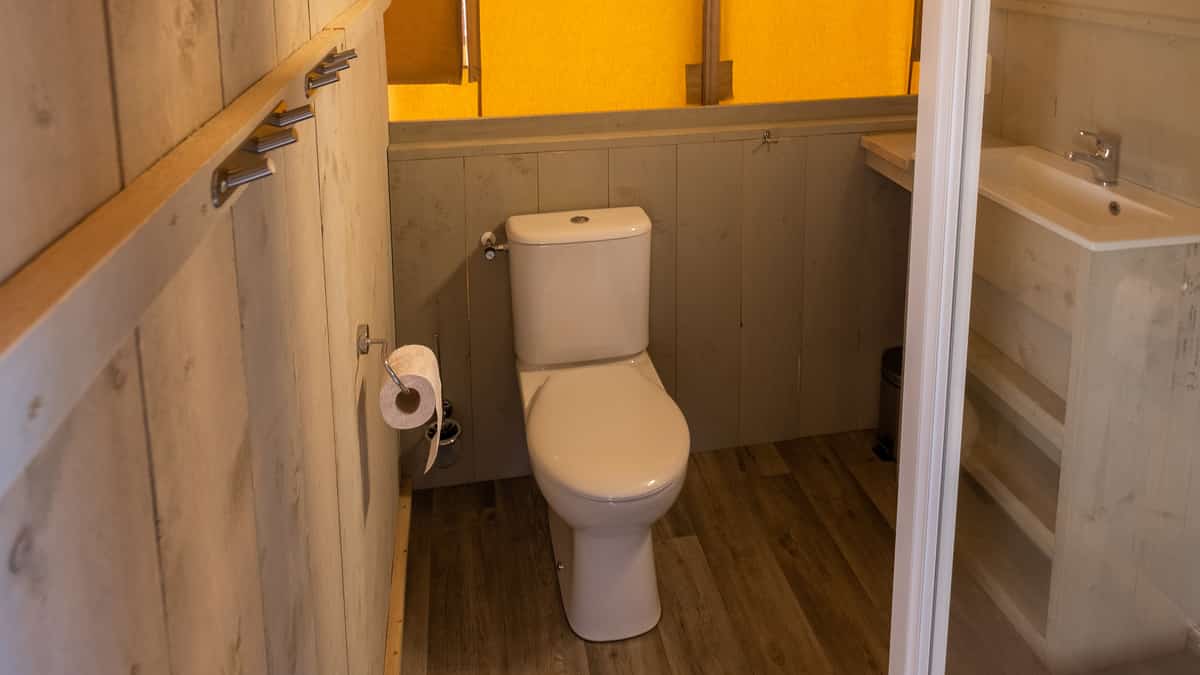 Badkamer met toilet, wastafel en gele rolgordijnen