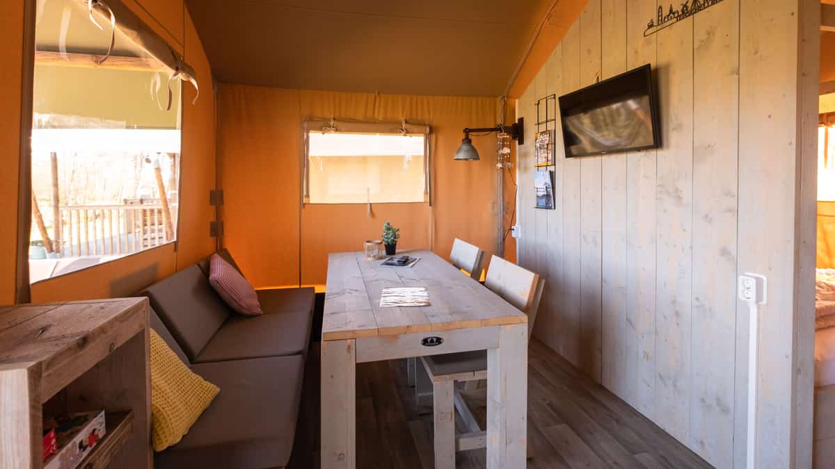 Zithoek met grijze bank, houten eettafel en grote ramen