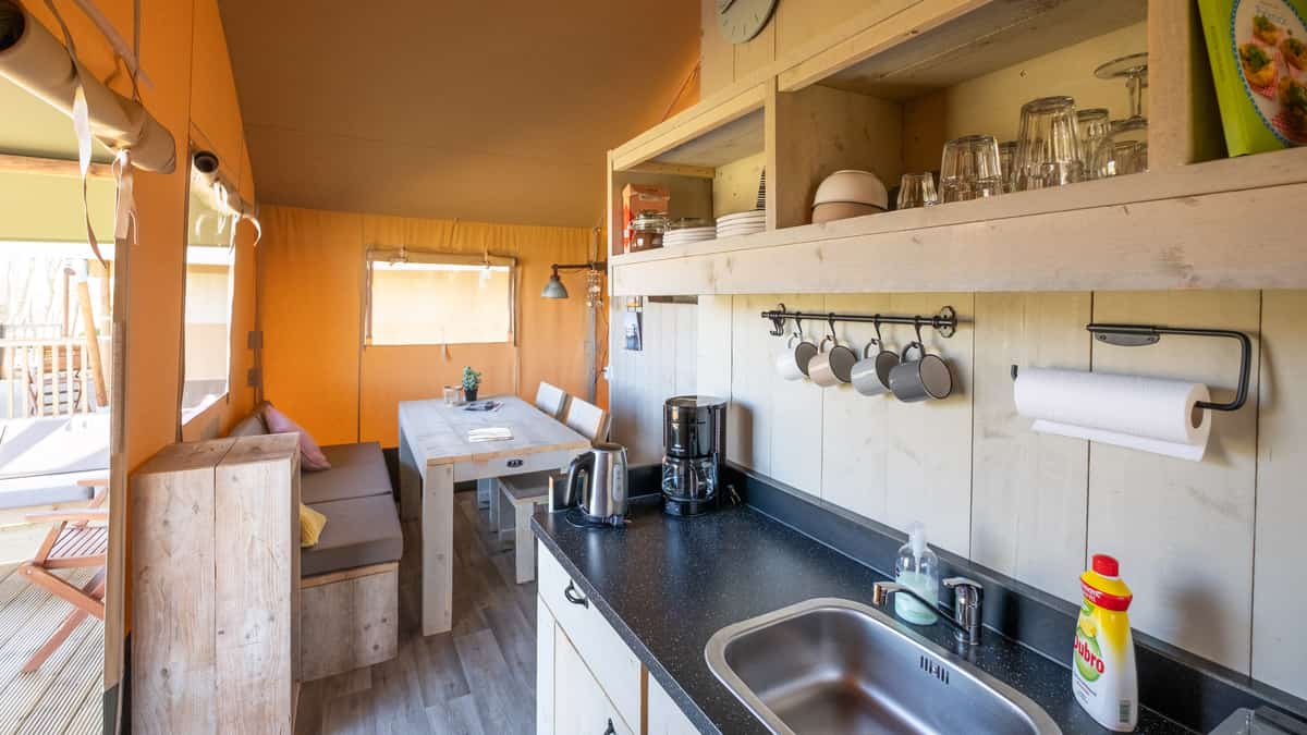 Keukenhoek met houten planken, hangende mokken en een spoelbak