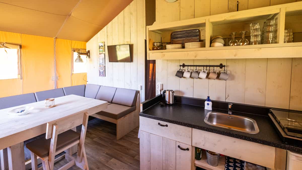 Eethoek met houten tafel, grijze banken en open keukenplanken