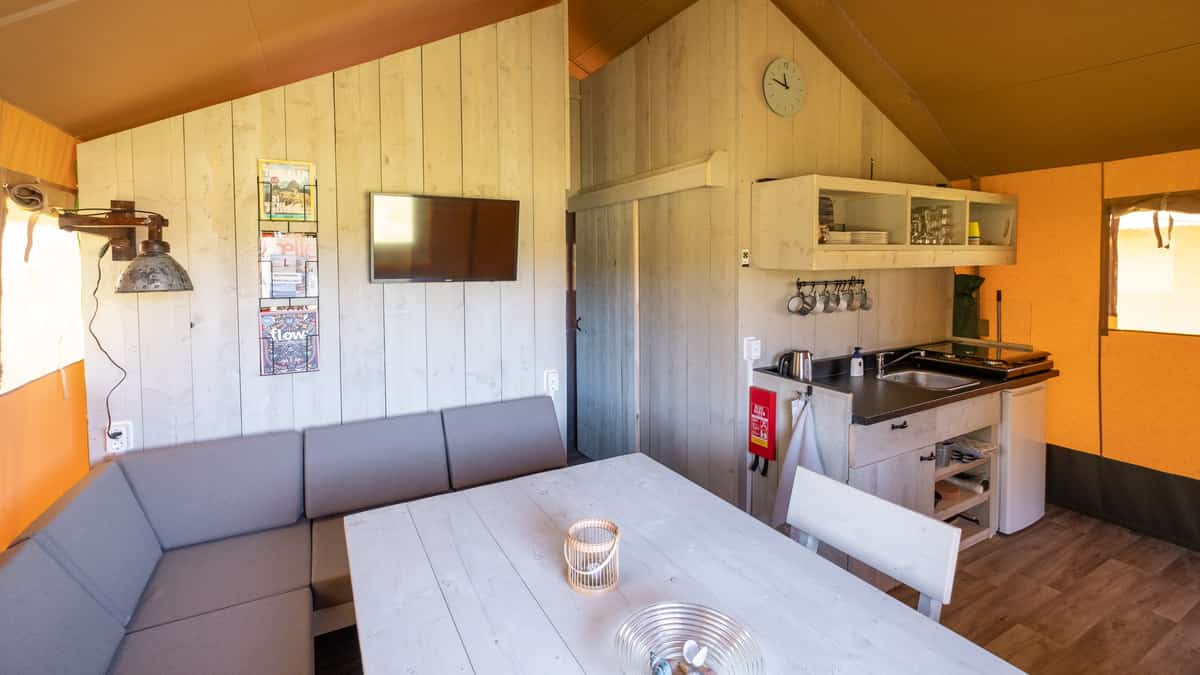 Zithoek met bank, tafel en kitchenette onder een tentdak