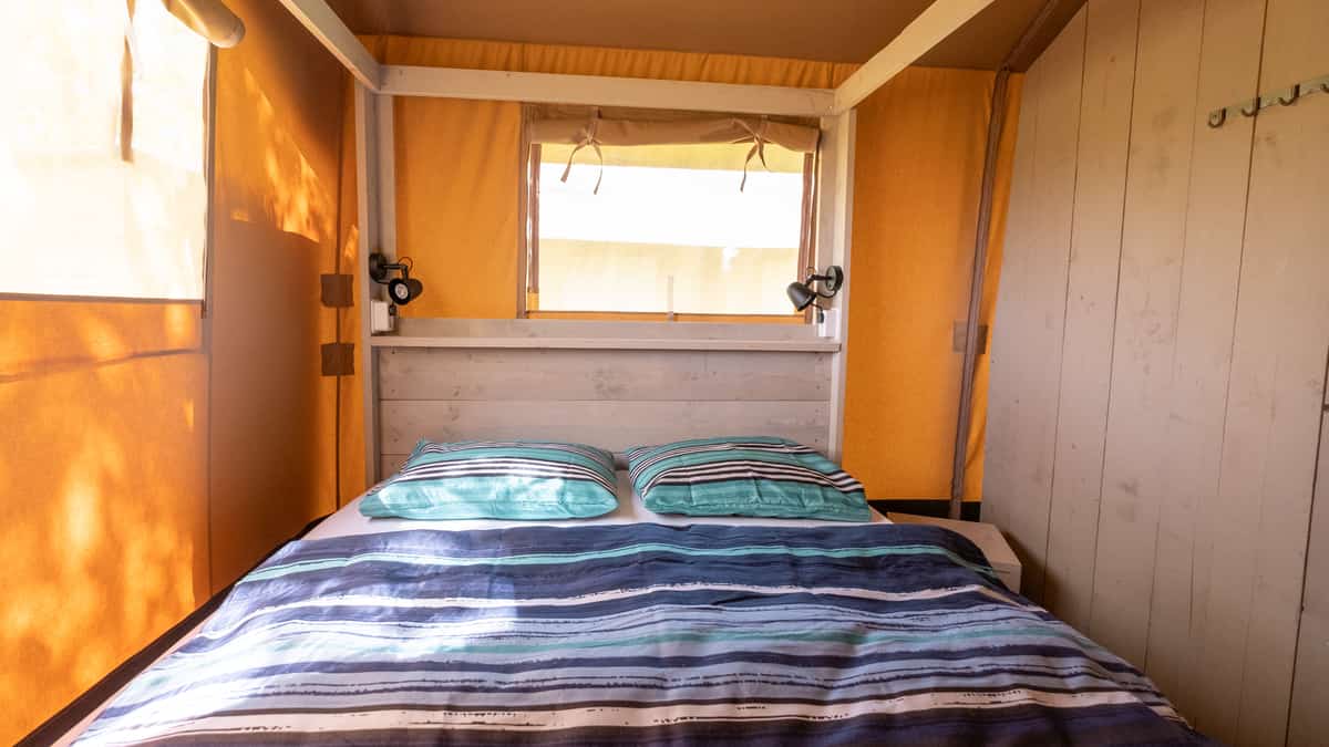 Bed met gestreept dekbed onder een houten balkenplafond