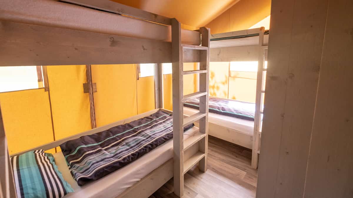 Houten stapelbedden met gestreept beddengoed en ladders