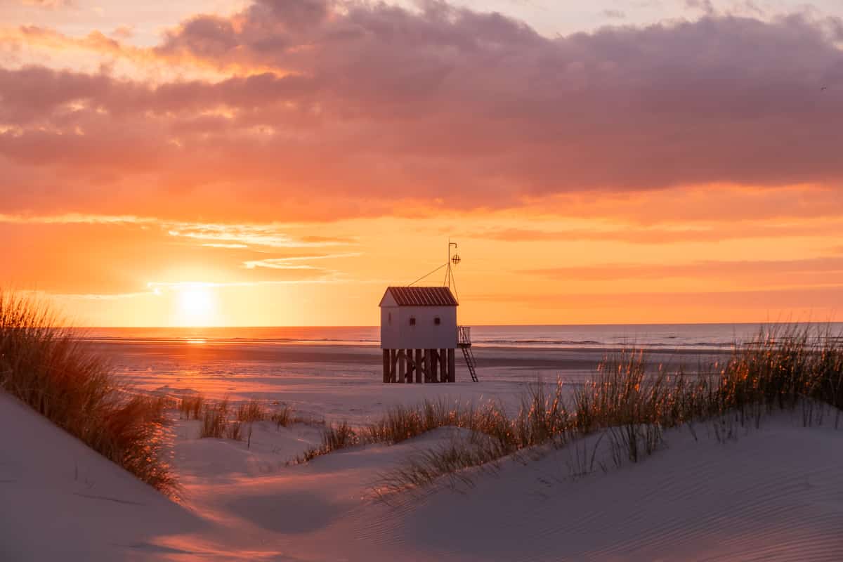 Strandhuisje op palen bij zonsondergang op het strand van Terschelling