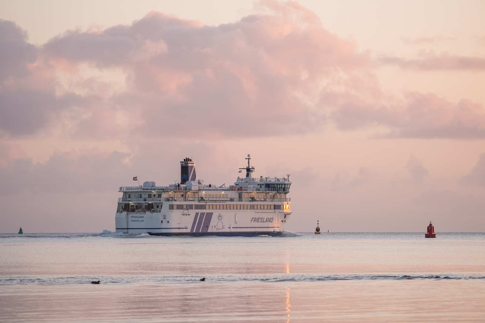 Veerboot Friesland op zee onder roze wolkenlucht bij schemering