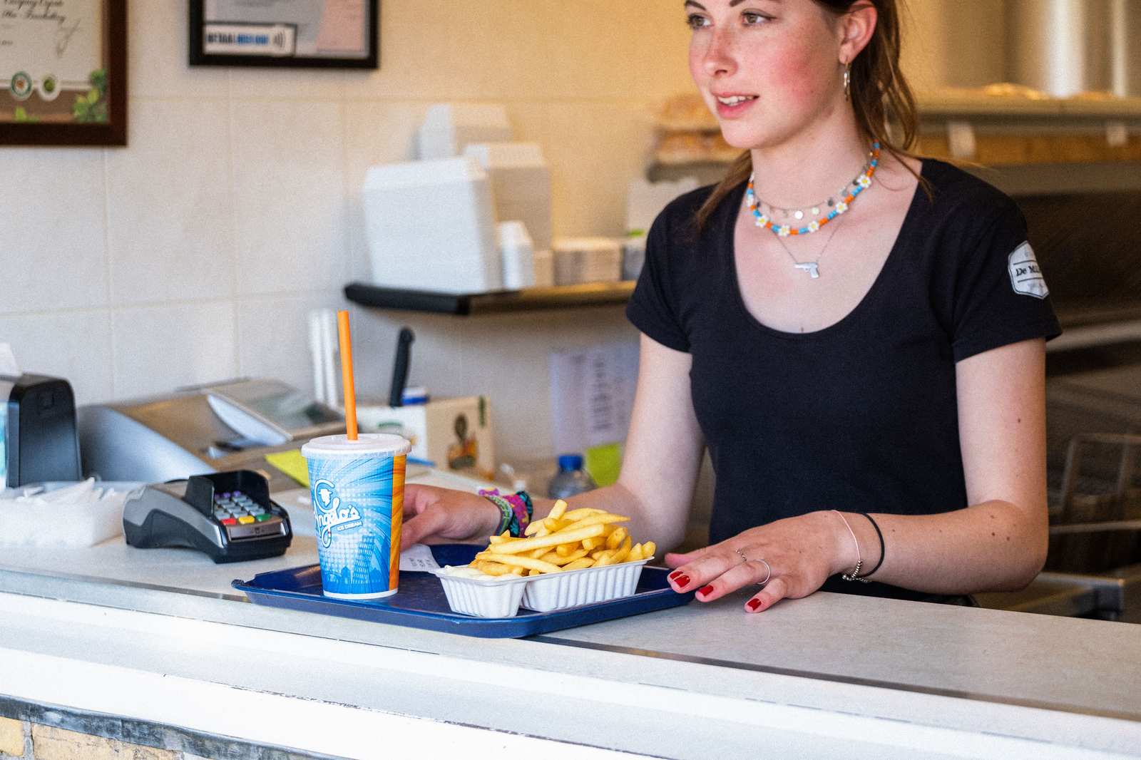 Medewerker overhandigt dienblad met friet en een drinkbeker aan een klant