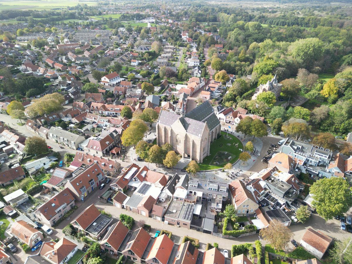 Luchtfoto van een dorp met kerk, huizen en omliggend bos