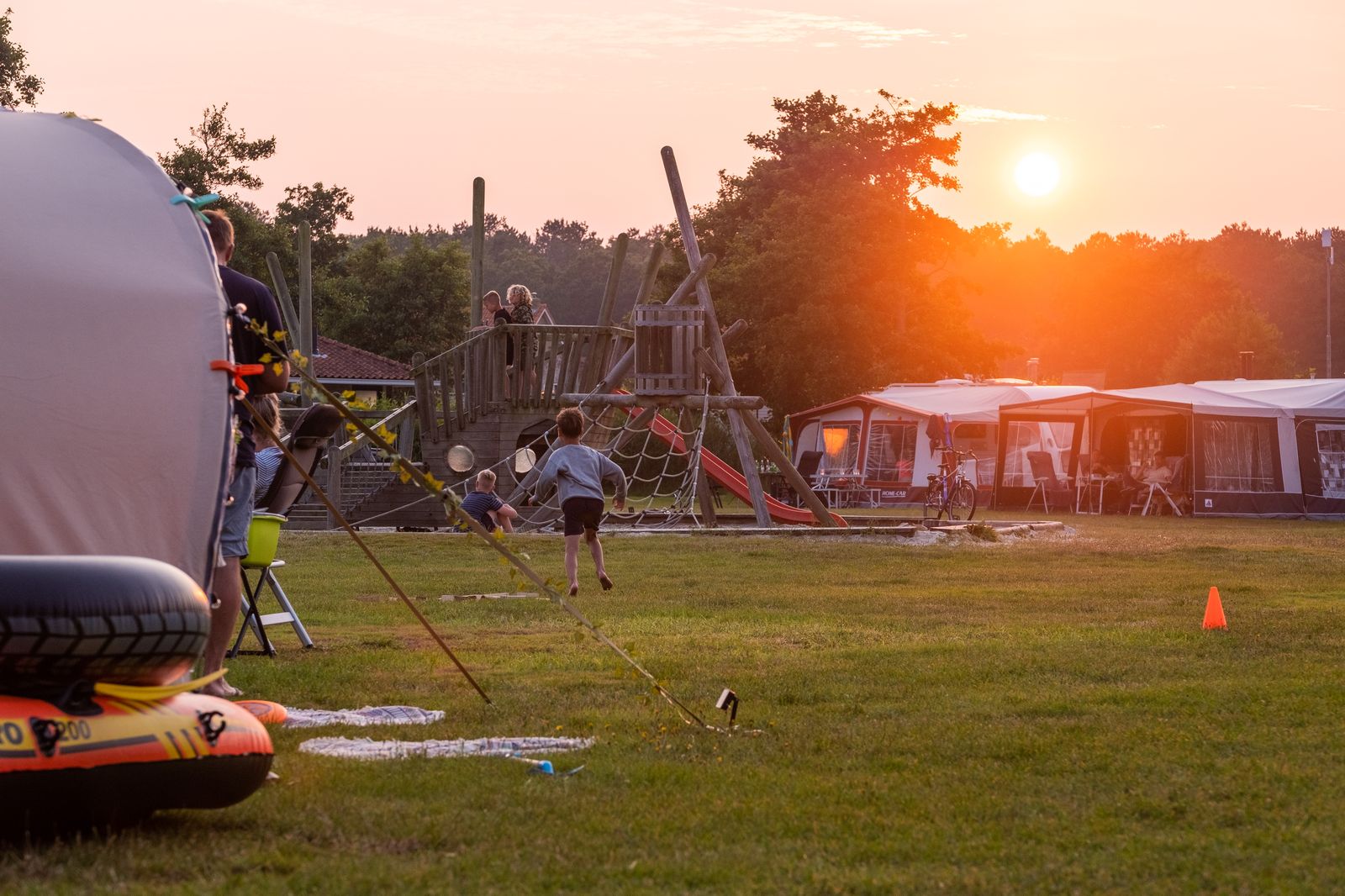 Kinderen spelen bij een houten klimtoestel in de avondzon