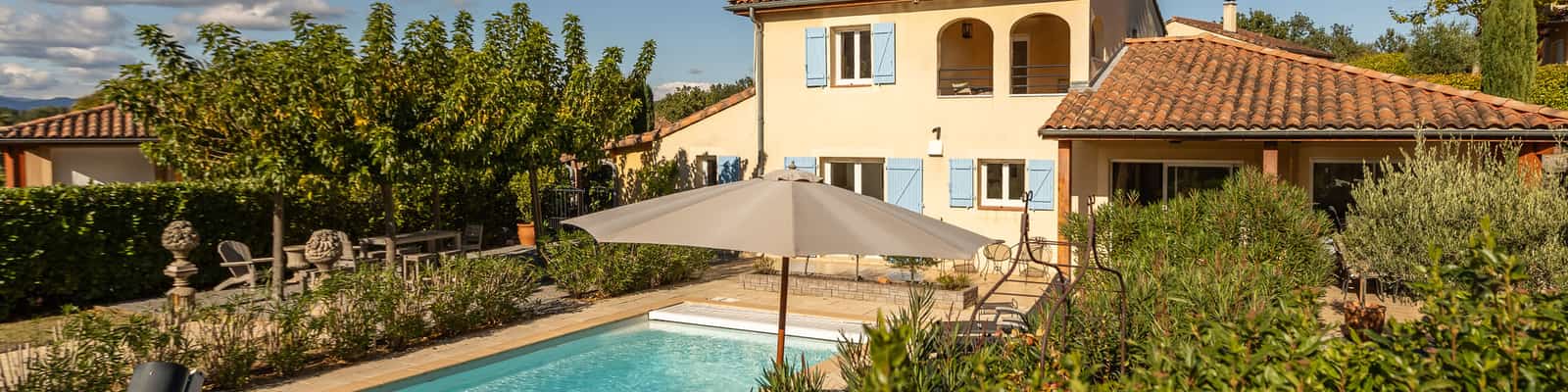 Buitenzwembad naast een villa met ligstoelen en parasol