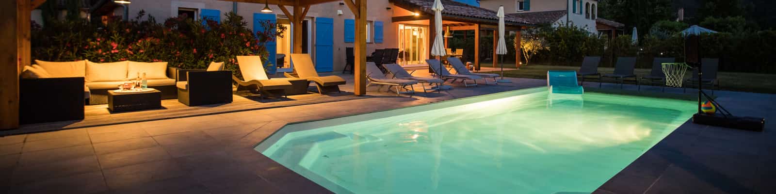 Verlichte zwembad bij villa met ligbedden en pergola