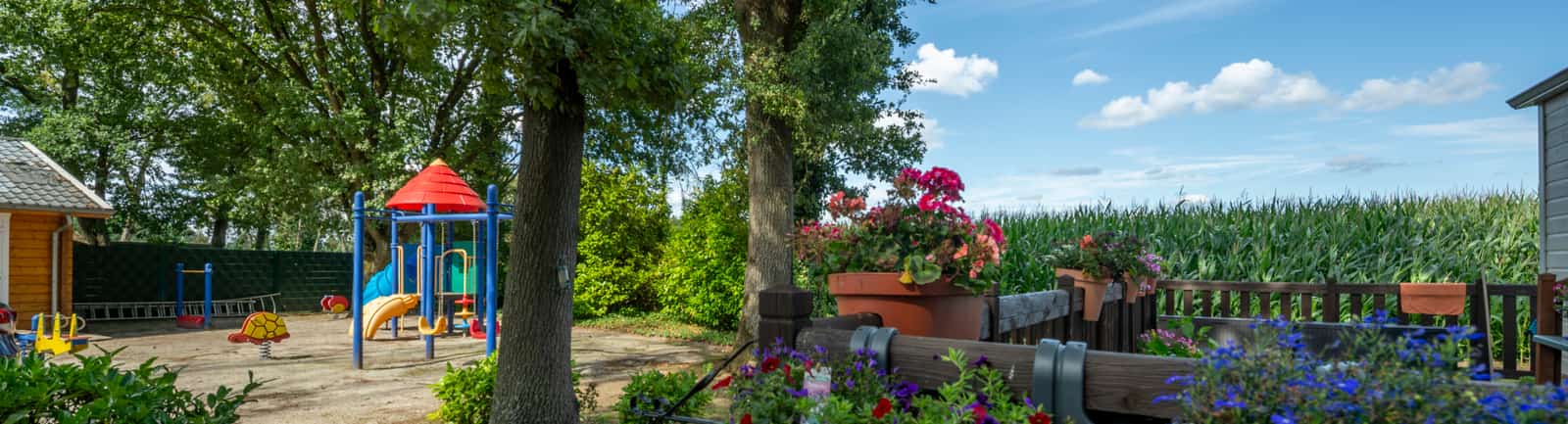 Speeltuin naast terras met bloemen en bomen