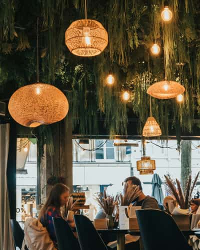 Gezellige restaurantzaal met hanglampen en groen aan het plafond