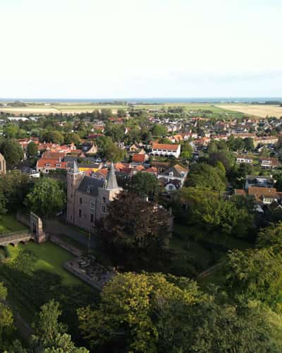 Luchtbeeld van kasteel en kerk tussen bomen en dorpshuizen