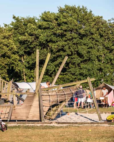 Kinderen bij houten speeltoestel met glijbaan en klimnet