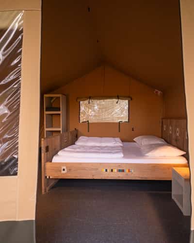Slaapkamer met tweepersoonsbed in een 2-persoons safaritent op Camping Cupido