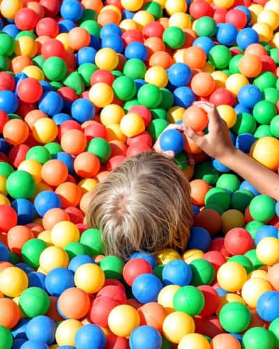 Kind speelt in een ballenbak met kleurrijke ballen