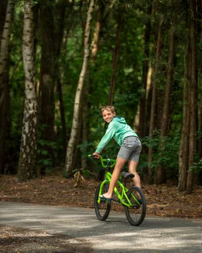 Jongen op groene fiets in bos