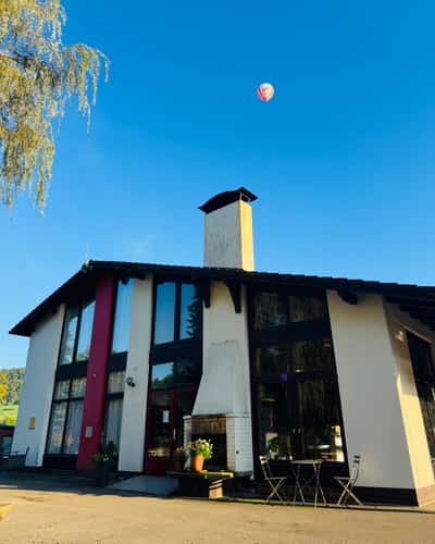 Modern huis met schoorsteen en luchtballon aan de blauwe lucht