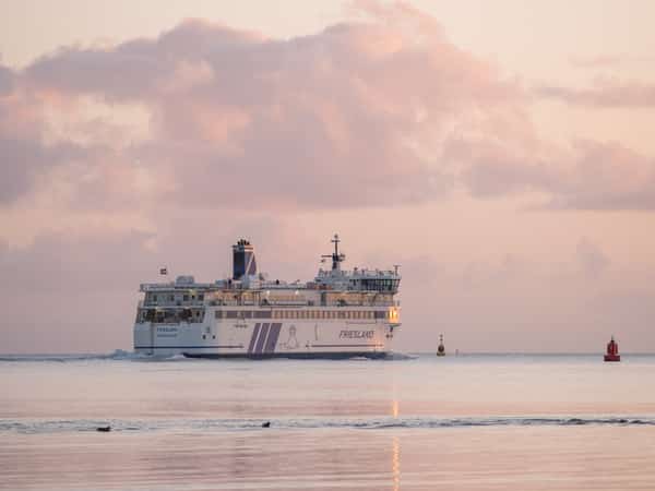 Veerboot Friesland op zee onder roze wolkenlucht bij schemering