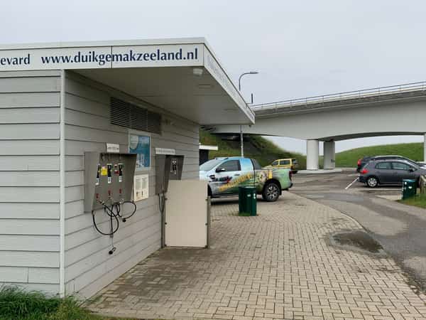 Vulstation voor duikflessen naast parkeerplaats en brug