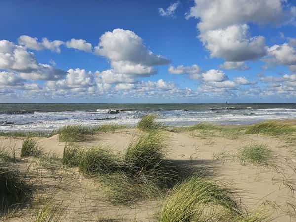 Zandduinen met helmgras aan zee onder een wolkenlucht