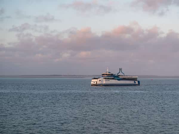 Twee veerboten op zee onder een roze bewolkte lucht