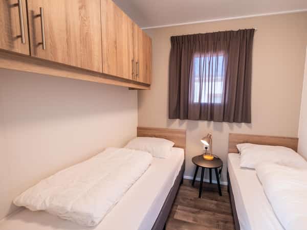 Slaapkamer met twee eenpersoonsbedden in Chalet Deluxe Duinroosje op Camping Cupido