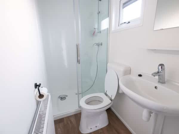 Badkamer met wastafel, spiegel, glazen douche en toilet