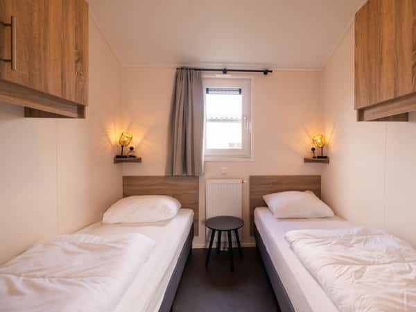 Slaapkamer met twee eenpersoonsbedden in Chalet Deluxe Kluut op Camping Cupido