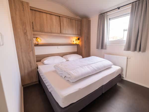 Slaapkamer met tweepersoonsbed in Chalet Deluxe Kluut op Camping Cupido