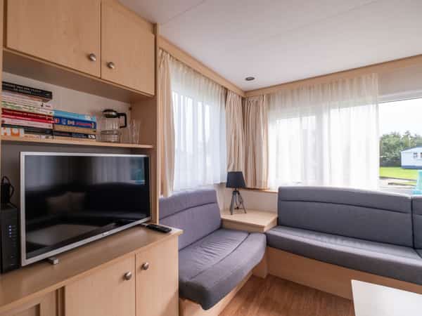 Woonkamer met bank en tv in stacaravan Lisa op Camping Cupido
