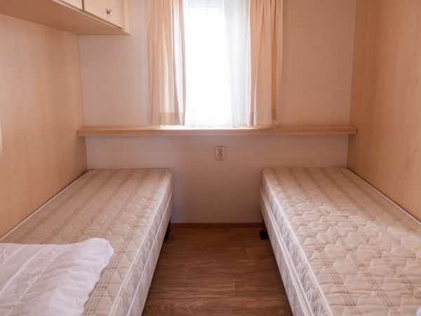 Slaapkamer met twee eenpersoonsbedden in stacaravan Lisa op Camping Cupido