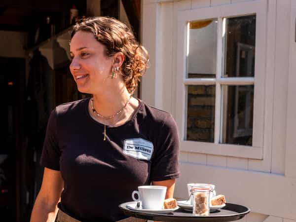 Medewerker van Eetcafé De Millem met een dienblad met drankjes