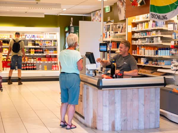 Kassa met klant in de RECRA Kampwinkel op Camping Cupido