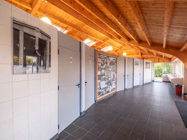 Gang met houten plafond in het toiletgebouw van Camping Cupido