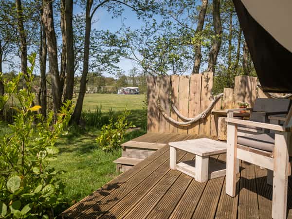 Terras met loungestoelen bij een safaritent op Camping Cupido