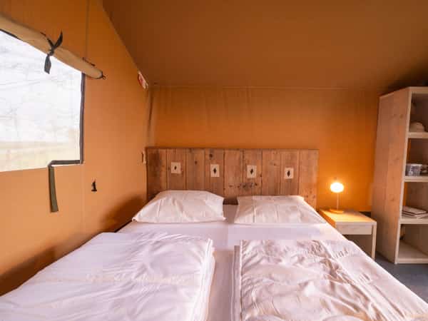 Slaapkamer met tweepersoonsbed in een safaritent op Camping Cupido