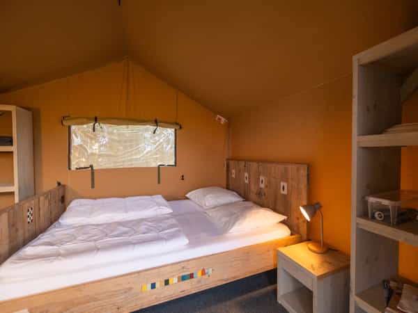 Slaapkamer met bed en kast in een safaritent op Camping Cupido