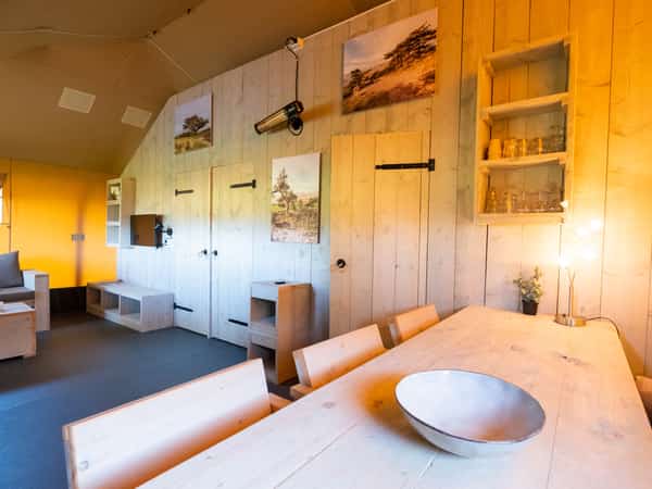 Zitruimte met houten tafels, stoelen en verlichte houten wanden
