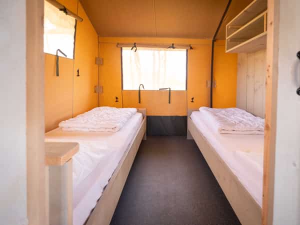 Slaapkamer met twee eenpersoonsbedden in een safaritent op Camping Cupido