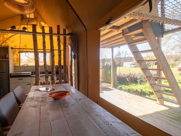 Eettafel en trap naar de slaapvide in een safaritent op Camping Cupido