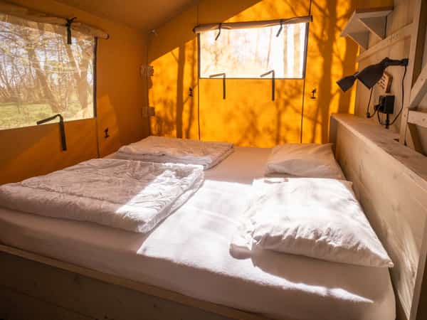 Slaapkamer met tweepersoonsbed in een safaritent op Camping Cupido
