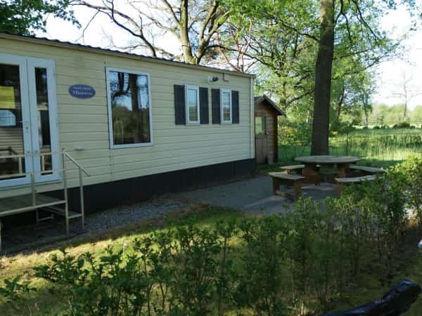 Vakantiehuisje met picknicktafel in een groene tuin