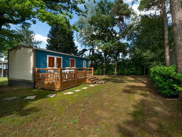 Mobil-home avec terrasse en bois dans un jardin arboré